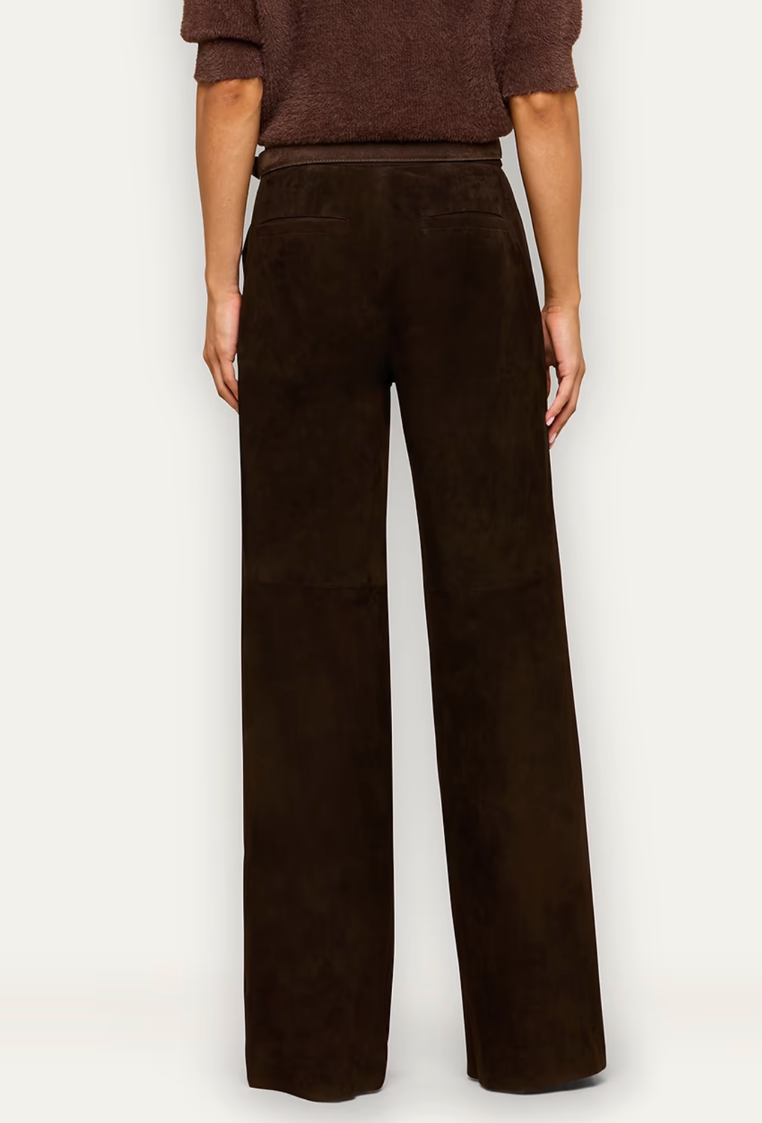 A model shown from the back wearing dark brown wide-leg trousers and a matching brown textured top, photographed against a clean off-white studio background.