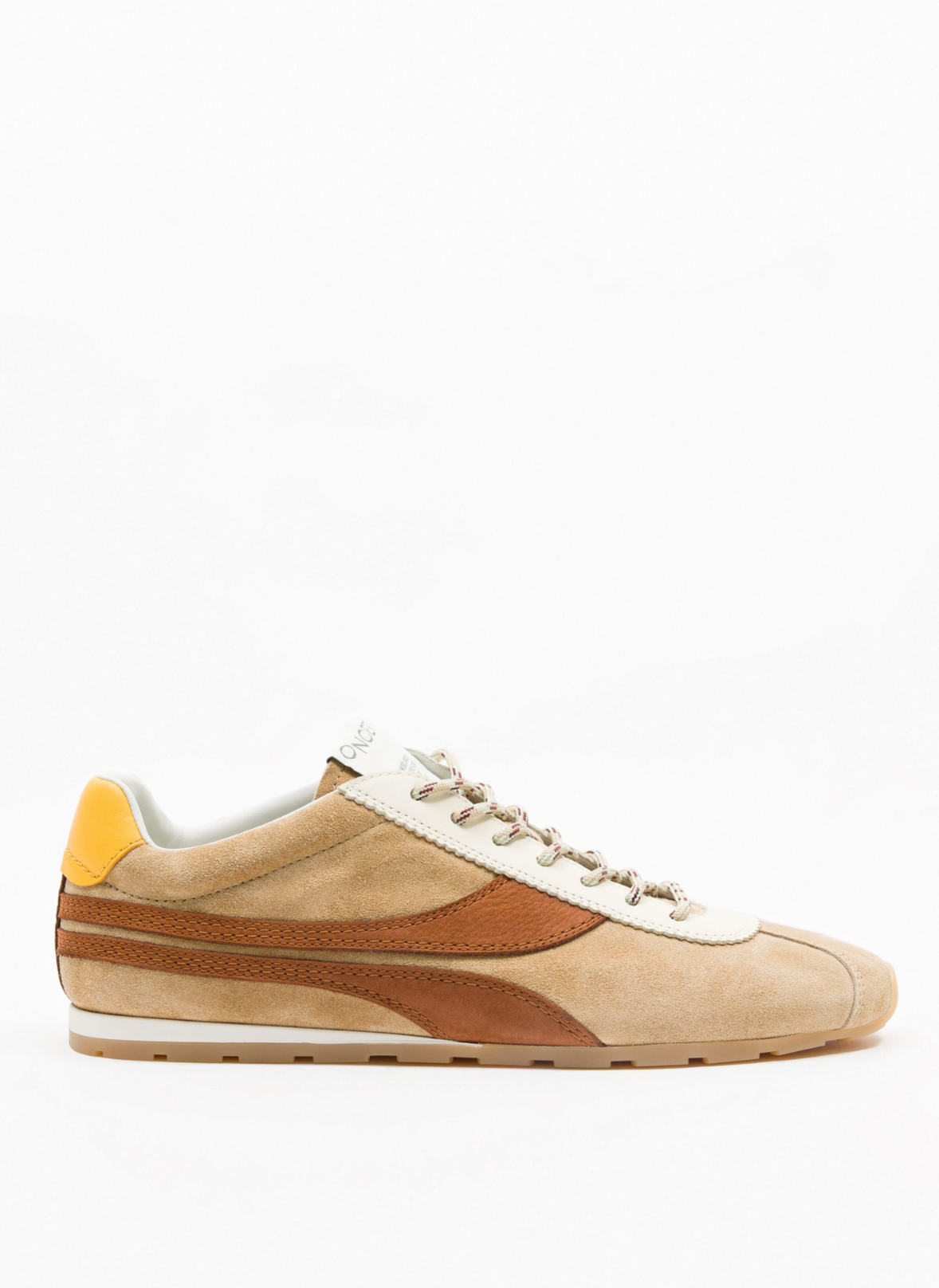 A low-top suede sneaker in beige and brown with a white leather side stripe, beige laces, a yellow heel tab, and a gum sole, shown in profile against a white background.