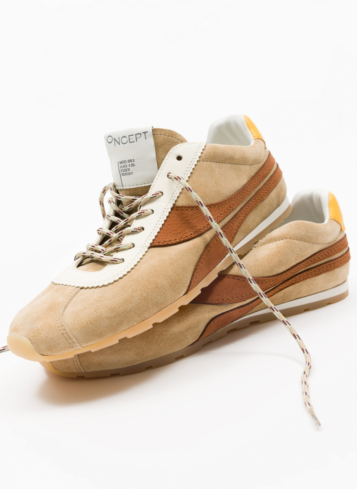 A pair of Concept brand retro-style sneakers in beige suede with brown leather side stripes, white laces, and a white tongue label, photographed on a clean white background.
