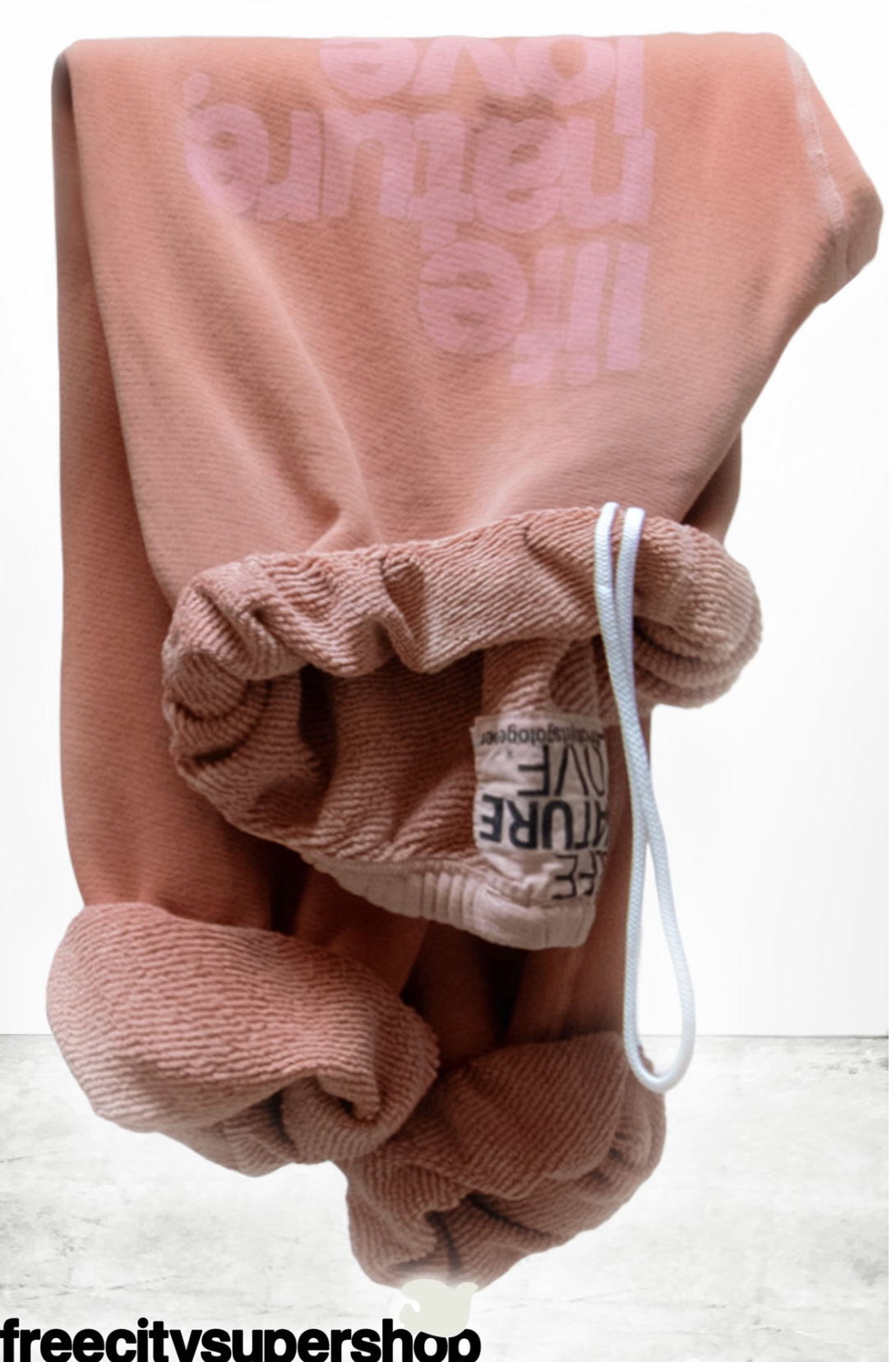 A dusty rose pink sweatshirt with 'the future love' printed in a lighter pink on the chest, featuring a gathered drawstring cuff with a white drawstring and a visible brand tag reading 'FIGURE LIVE'.