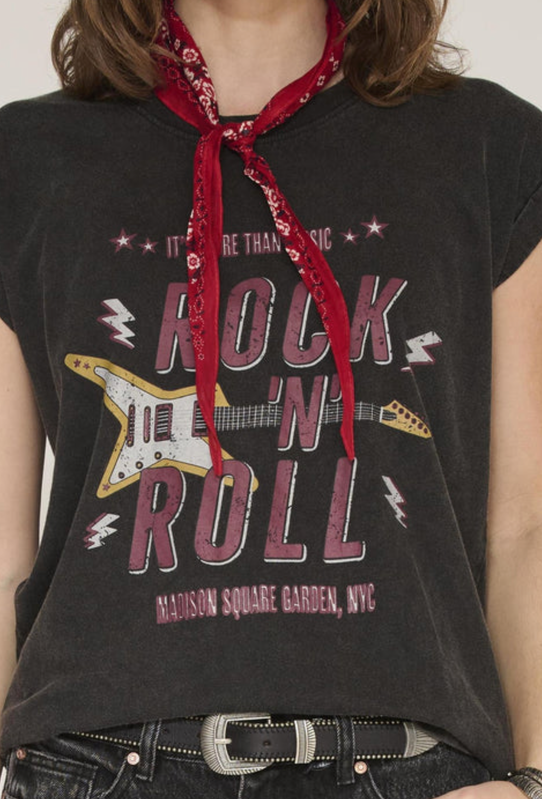 A close-up of a person wearing a dark charcoal gray graphic t-shirt with a distressed red, white, and blue bandana tied around the neck. The t-shirt features a graphic print of a yellow electric guitar and the text 'ROCK 'N ROLL' and 'MADISON SQUARE GARDEN, NYC'.